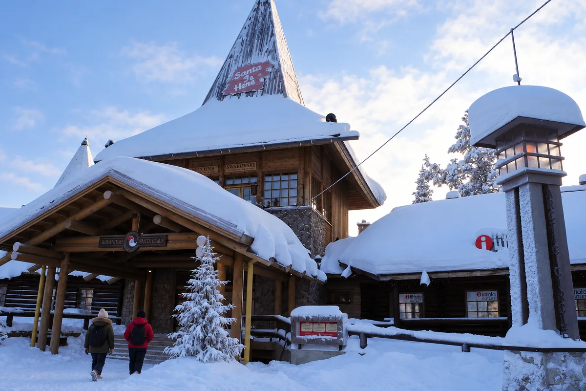 Ingresso innevato del Villaggio di Babbo Natale a Rovaniemi, con la torre di legno, il tetto carico di neve e le lanterne